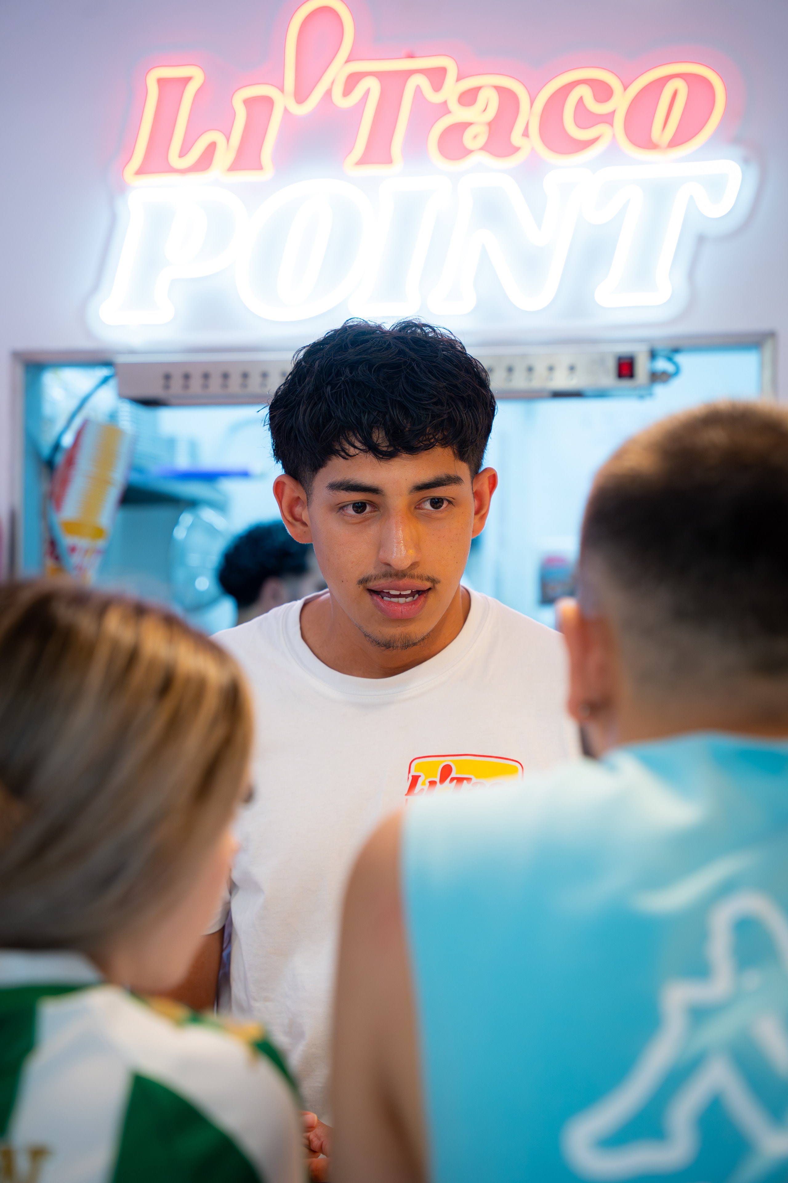 Un chico de Li'Taco atiende en la barra, bajo el neón Li'Taco Point