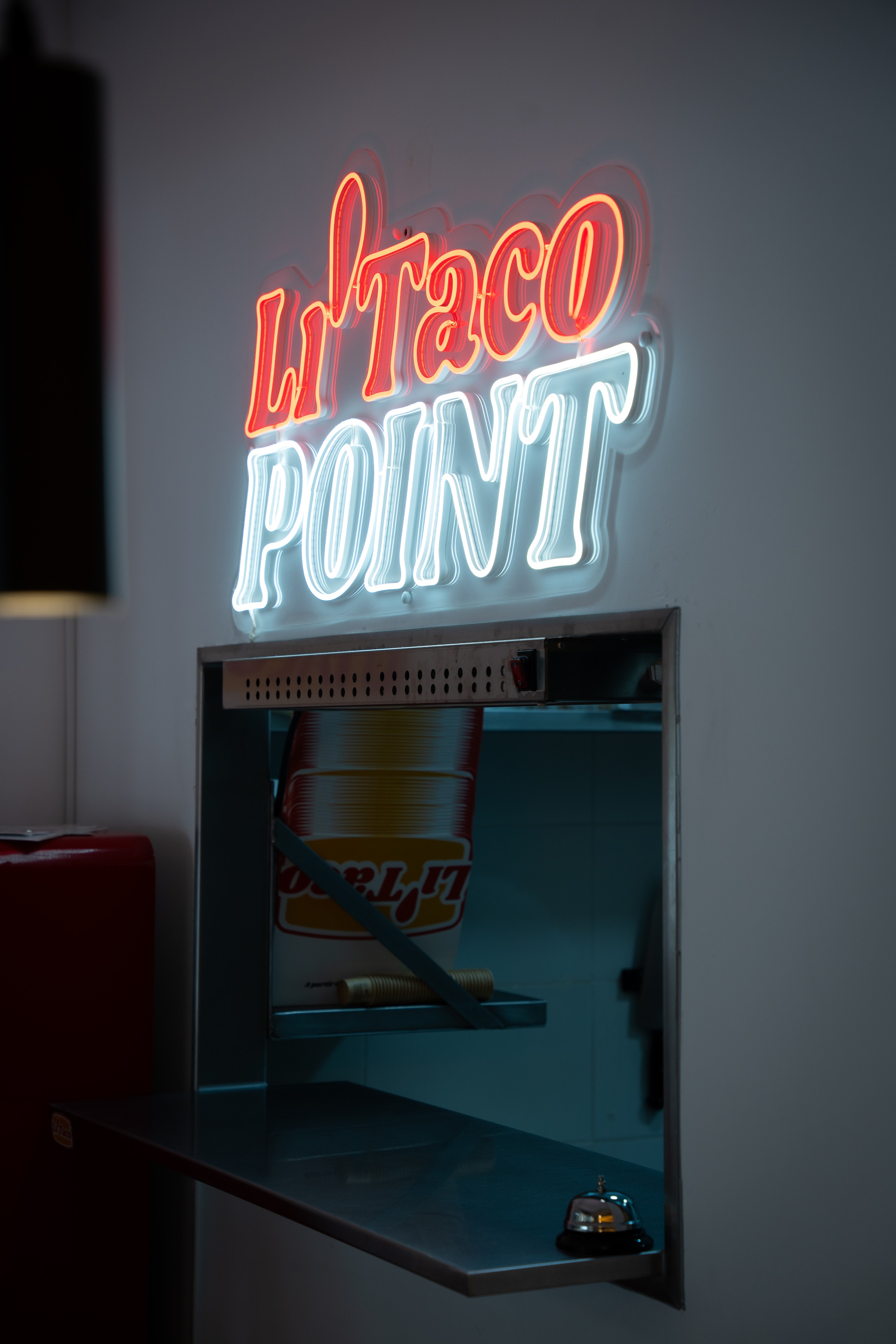 El neón Li'Taco Point encima de la ventanilla de la cocina, con un timbre en el mostrador