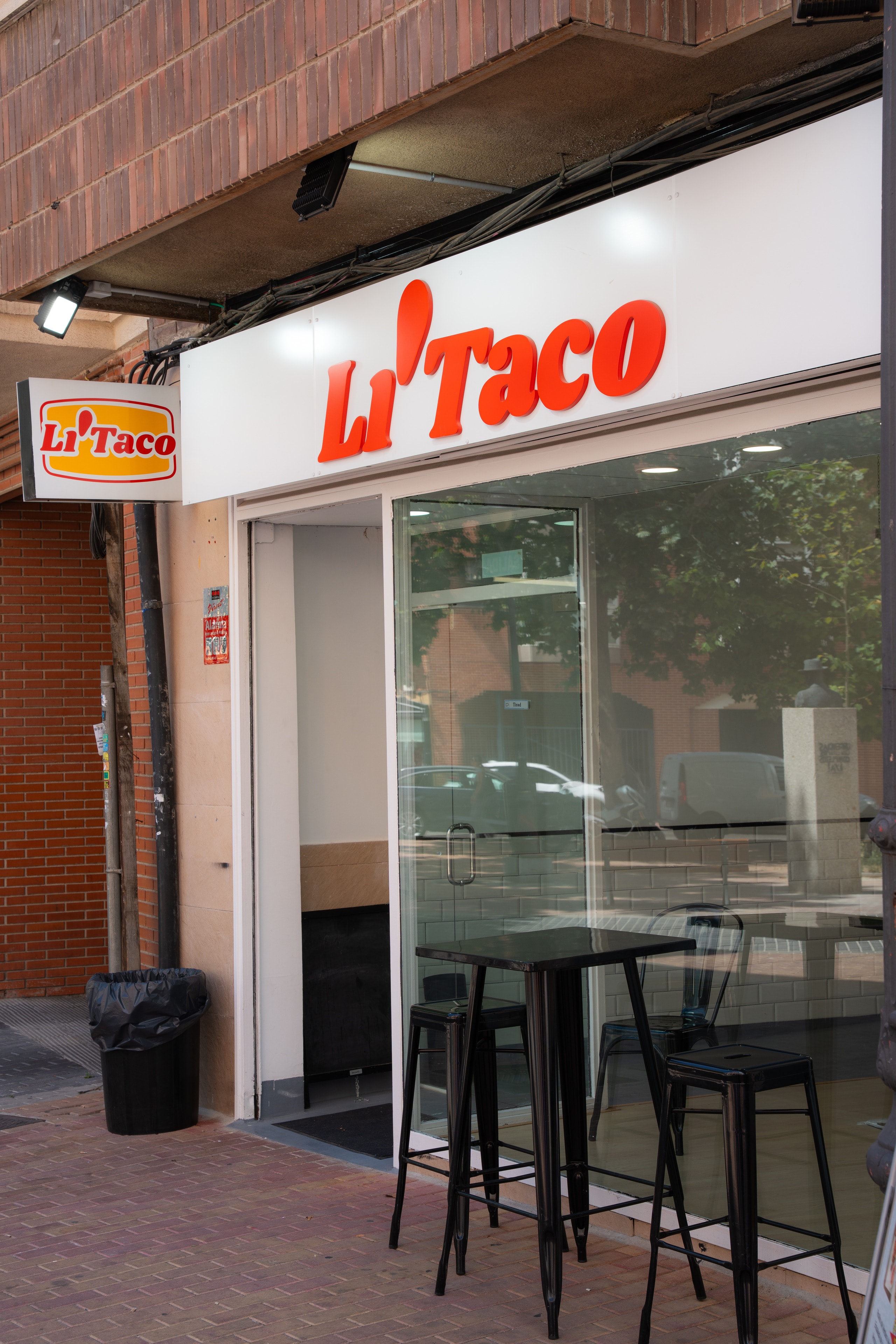 La fachada de Li'Taco en la calle San Eugenio: rótulo rojo sobre blanco, la caja de luz con el logo y el escaparate