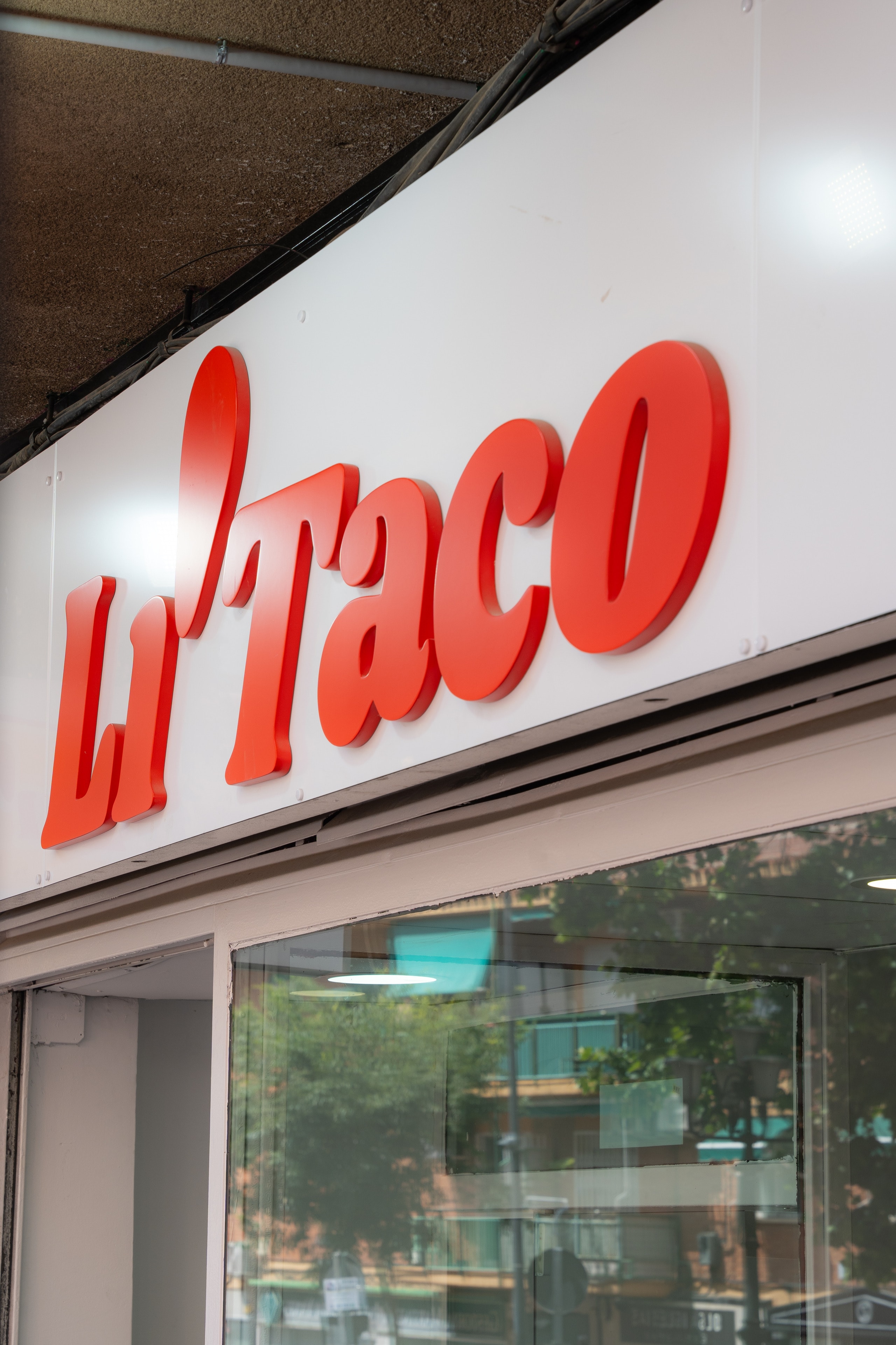 El rótulo rojo de Li'Taco sobre la fachada blanca, visto en diagonal desde la acera