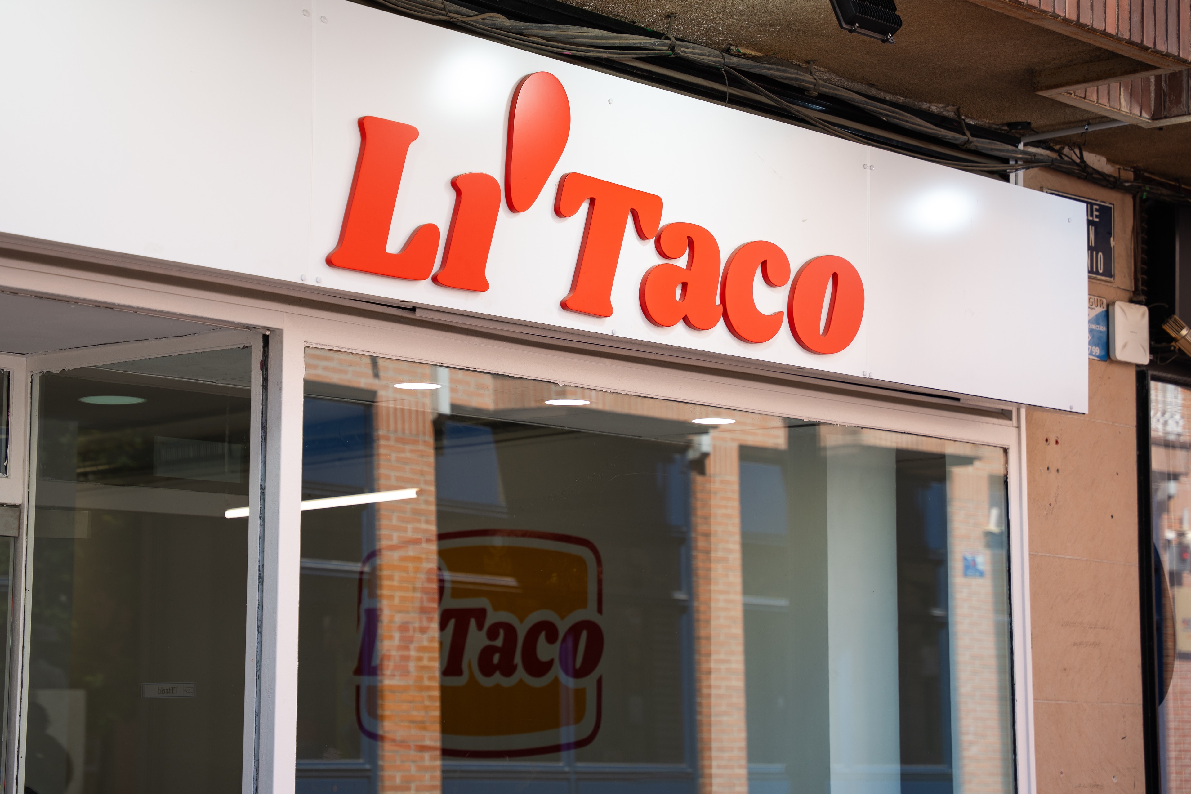 El rótulo de Li'Taco sobre el escaparate, con el logo de la pared reflejado en el cristal
