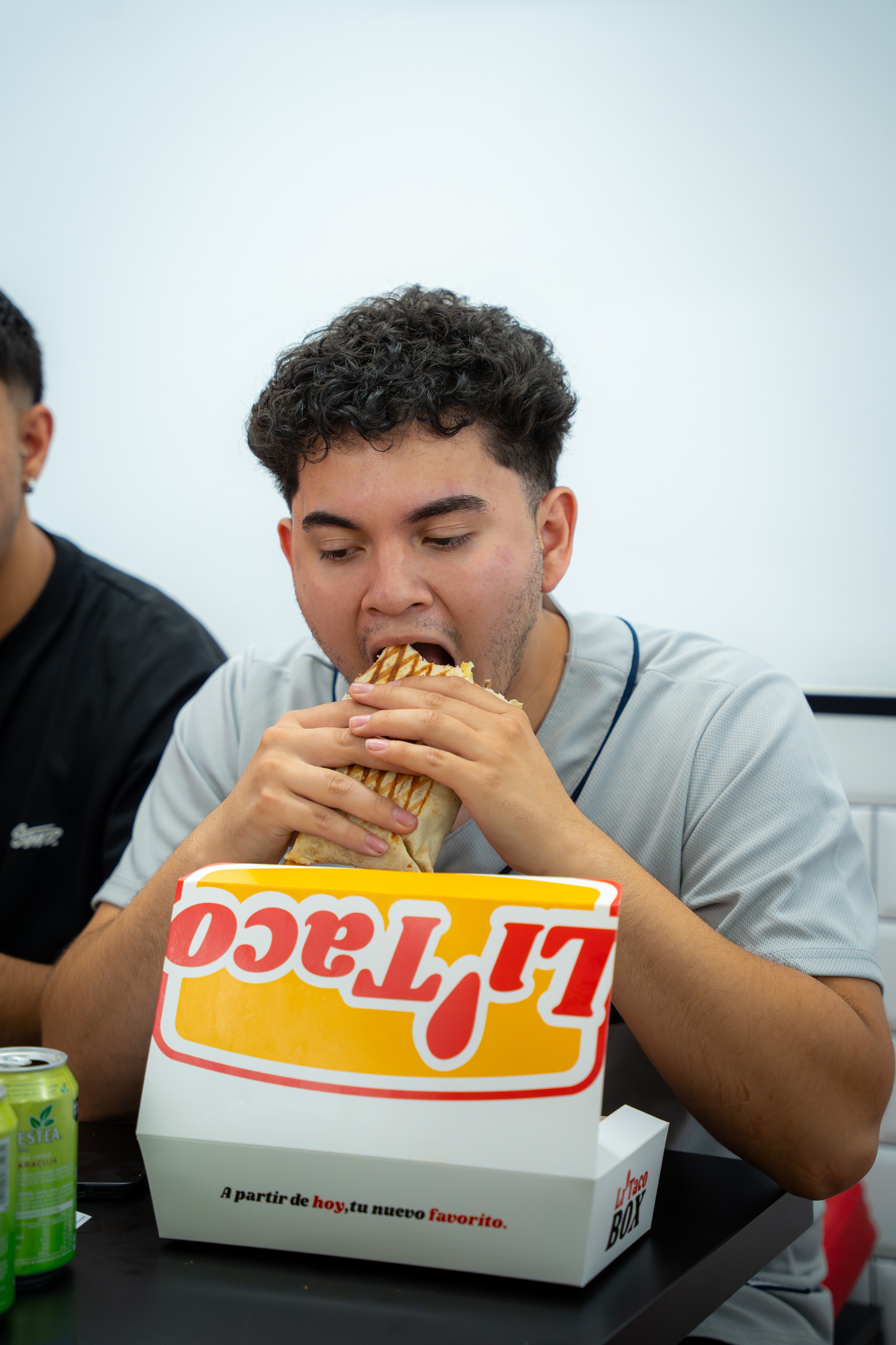 Un chico muerde su taco sobre una caja LiTaco abierta