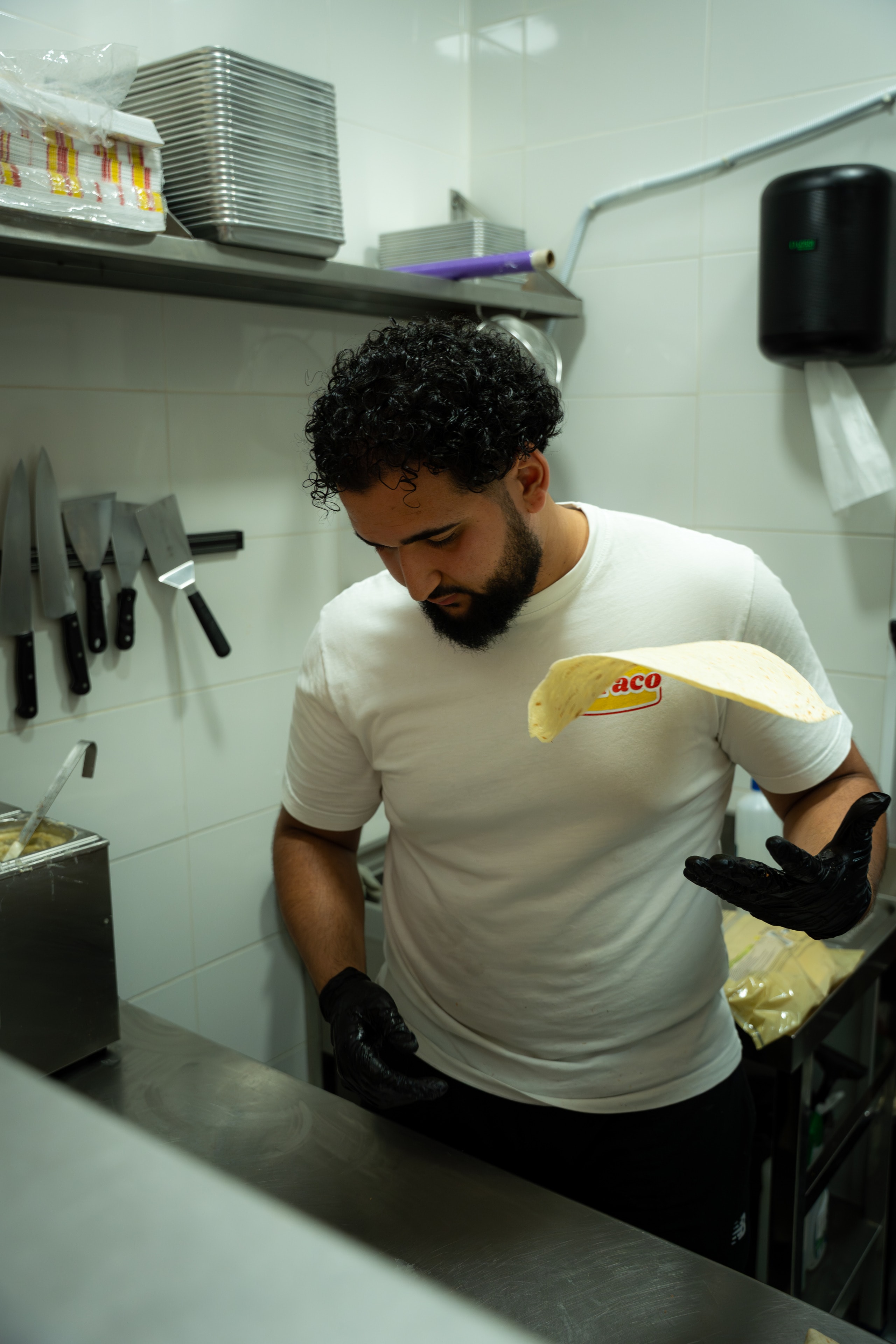 Un cocinero con guantes negros sostiene una tortilla en la cocina